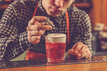 Image showing Barman making an alcoholic cocktail at the bar counter on the bar background