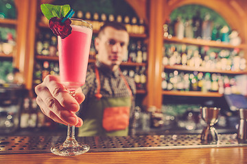 Image showing Barman offering an alcoholic cocktail at the bar counter on the bar background