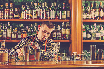 Image showing Barman making an alcoholic cocktail at the bar counter on the bar background