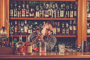 Image showing Barman making an alcoholic cocktail at the bar counter on the bar background