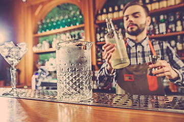 Image showing Barman making an alcoholic cocktail at the bar counter on the bar background