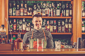 Image showing Barman offering an alcoholic cocktail at the bar counter on the bar background