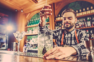 Image showing Barman making an alcoholic cocktail at the bar counter on the bar background