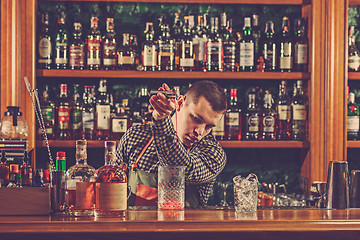 Image showing Barman making an alcoholic cocktail at the bar counter on the bar background