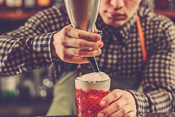 Image showing Barman making an alcoholic cocktail at the bar counter on the bar background