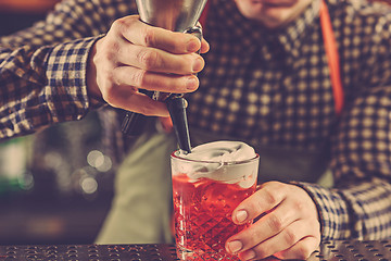 Image showing Barman making an alcoholic cocktail at the bar counter on the bar background