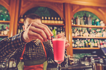 Image showing Barman making an alcoholic cocktail at the bar counter on the bar background