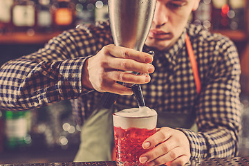 Image showing Barman making an alcoholic cocktail at the bar counter on the bar background