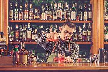 Image showing Barman making an alcoholic cocktail at the bar counter on the bar background