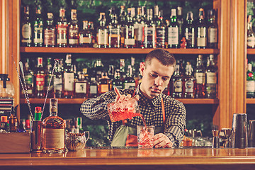 Image showing Barman making an alcoholic cocktail at the bar counter on the bar background