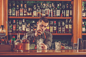 Image showing Barman making an alcoholic cocktail at the bar counter on the bar background