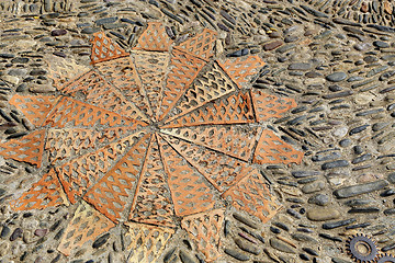 Image showing Patterned floor with sea pebbles red bricks and metal gears