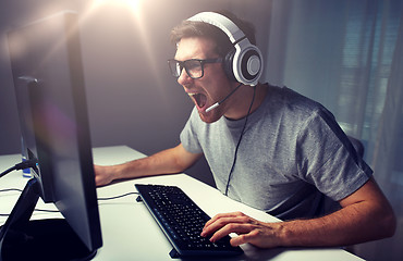 Image showing man in headset playing computer video game at home