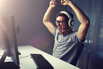 Image showing man in headset playing computer video game at home