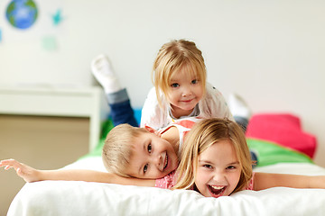 Image showing happy little kids having fun in bed at home