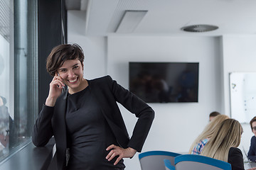 Image showing Elegant Woman Using Mobile Phone by window in office building