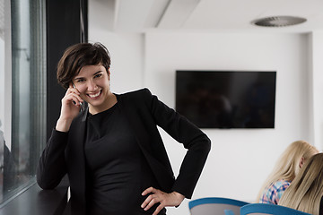 Image showing Elegant Woman Using Mobile Phone by window in office building