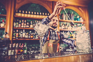 Image showing Barman making an alcoholic cocktail at the bar counter on the bar background