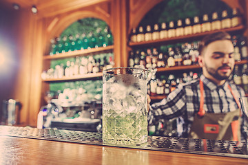 Image showing Barman making an alcoholic cocktail at the bar counter on the bar background