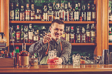 Image showing Barman making an alcoholic cocktail at the bar counter on the bar background