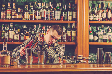 Image showing Barman making an alcoholic cocktail at the bar counter on the bar background