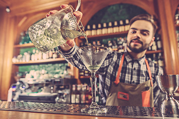 Image showing Barman making an alcoholic cocktail at the bar counter on the bar background