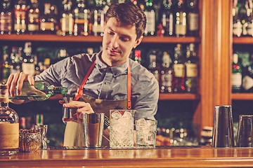 Image showing Expert barman is making cocktail at night club.