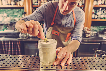 Image showing Expert barman is making cocktail at night club.