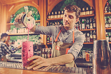 Image showing Expert barman is making cocktail at night club.