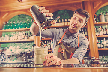 Image showing Expert barman is making cocktail at night club.