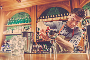 Image showing Expert barman is making cocktail at night club.