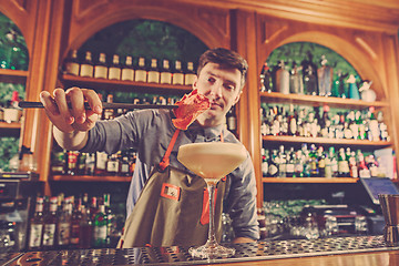 Image showing Expert barman is making cocktail at night club.