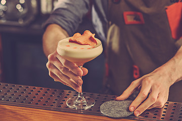 Image showing Barman offering an alcoholic cocktail at the bar counter on the bar background