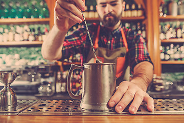 Image showing Barman making an alcoholic cocktail at the bar counter on the bar background