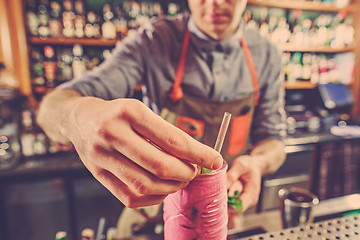 Image showing Expert barman is making cocktail at night club.