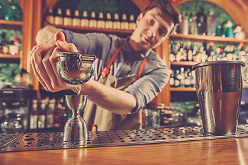 Image showing Expert barman is making cocktail at night club.