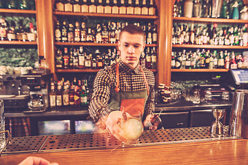 Image showing Barman making an alcoholic cocktail at the bar counter on the bar background