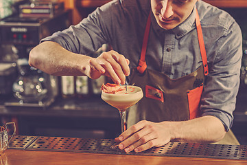 Image showing Expert barman is making cocktail at night club.