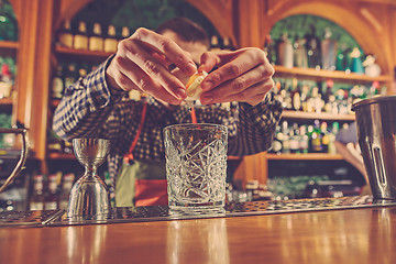 Image showing Barman making an alcoholic cocktail at the bar counter on the bar background