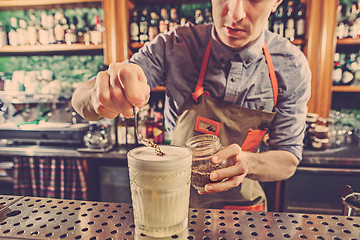 Image showing Expert barman is making cocktail at night club.