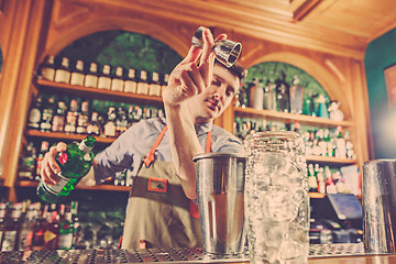 Image showing Expert barman is making cocktail at night club.