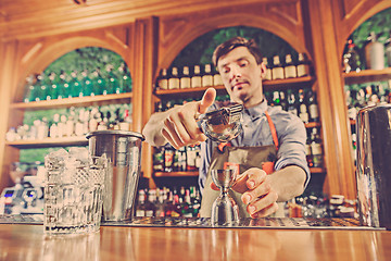 Image showing Expert barman is making cocktail at night club.