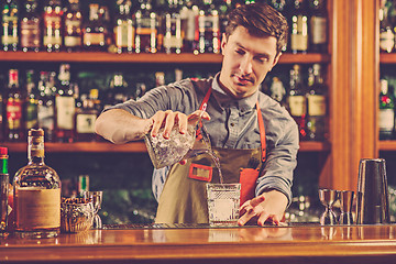 Image showing Expert barman is making cocktail at night club.