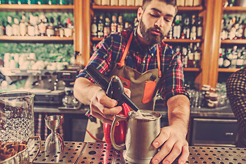 Image showing Barman making an alcoholic cocktail at the bar counter on the bar background