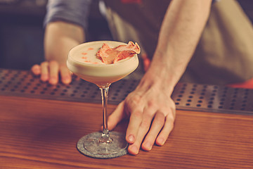 Image showing Barman offering an alcoholic cocktail at the bar counter on the bar background