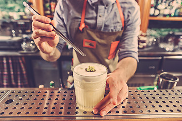 Image showing Expert barman is making cocktail at night club.