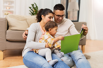 Image showing happy family with baby reading book at home