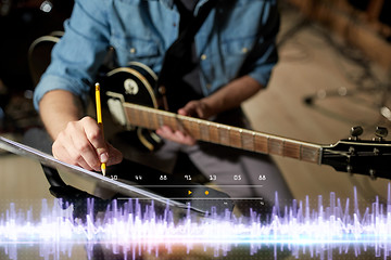 Image showing musician with guitar and music book at studio