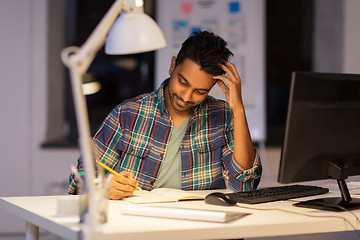 Image showing creative man with notebook working at night office