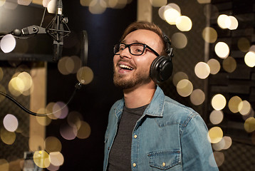 Image showing man with headphones singing at recording studio